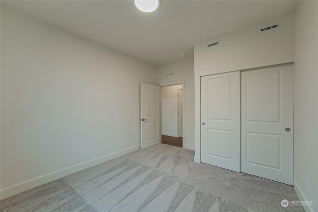 unfurnished bedroom featuring light carpet and a closet