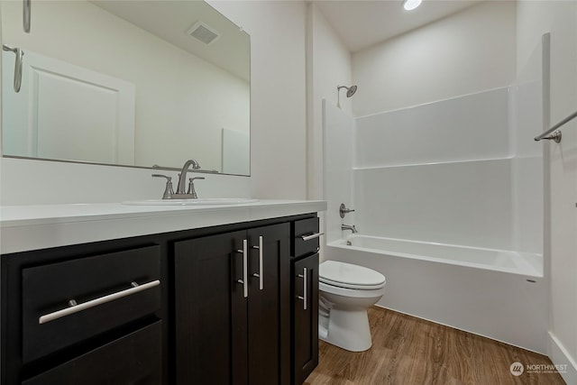 full bathroom with hardwood / wood-style floors, vanity, toilet, and shower / washtub combination