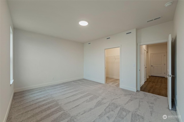 unfurnished bedroom with light carpet, a spacious closet, and a closet