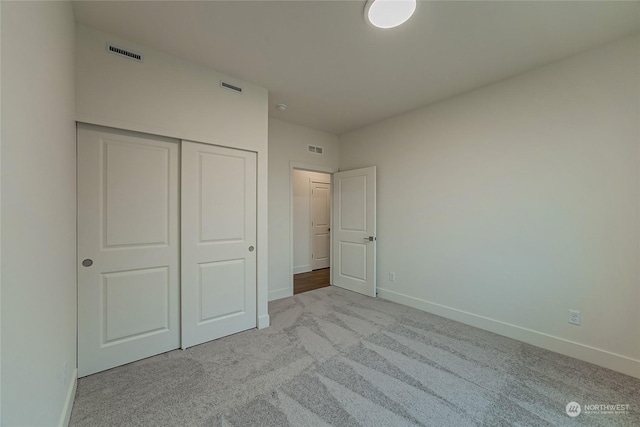 unfurnished bedroom with light carpet and a closet