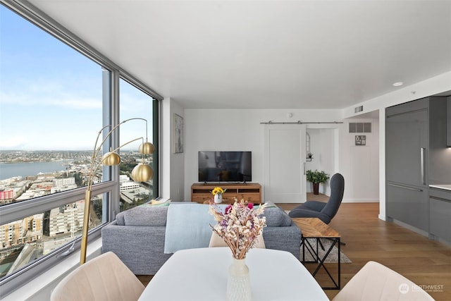 living room featuring a barn door, a wall of windows, wood-type flooring, and a water view