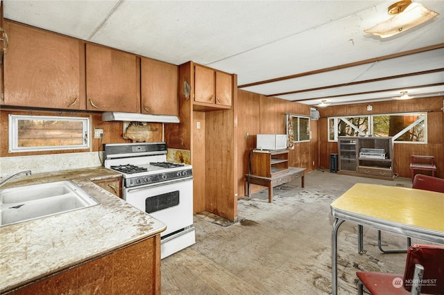 kitchen featuring white appliances, wood walls, and sink