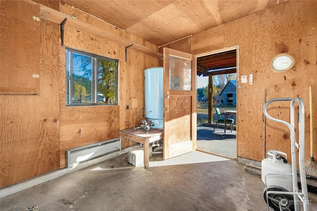 miscellaneous room with concrete flooring, wooden walls, and a baseboard heating unit