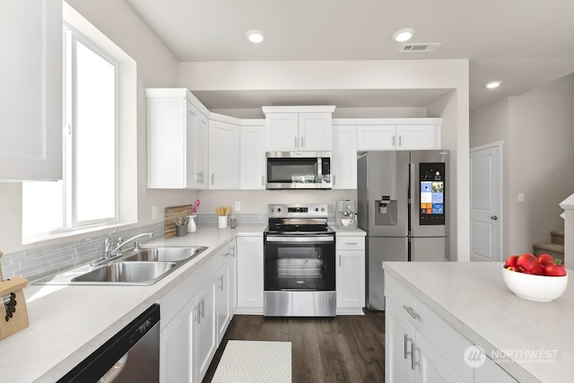 kitchen with sink, tasteful backsplash, dark hardwood / wood-style floors, stainless steel appliances, and white cabinets