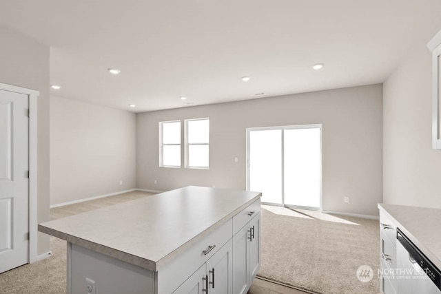 kitchen featuring dishwasher, a center island, light carpet, and white cabinets