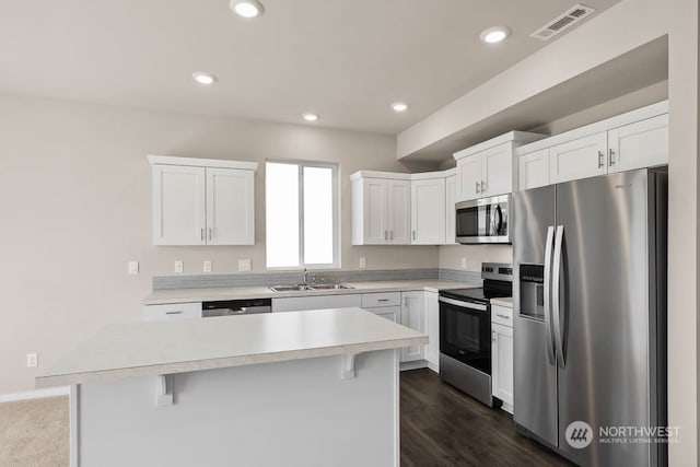 kitchen featuring white cabinetry, a center island, appliances with stainless steel finishes, and a breakfast bar