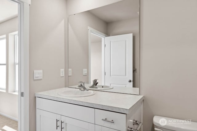 bathroom with plenty of natural light, toilet, and vanity