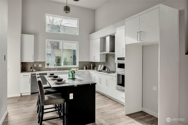 8904 NE 173rd Pl Unit B, Bothell, WA 98011 - kitchen with wall chimney exhaust hood, appliances with stainless steel finishes, a sink, a towering ceiling, and decorative backsplash