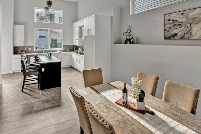 dining space featuring light hardwood / wood-style floors and a towering ceiling