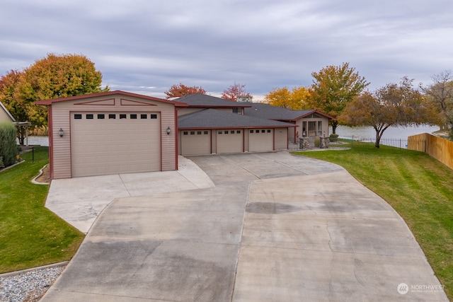 single story home featuring a garage, a front lawn, and a water view