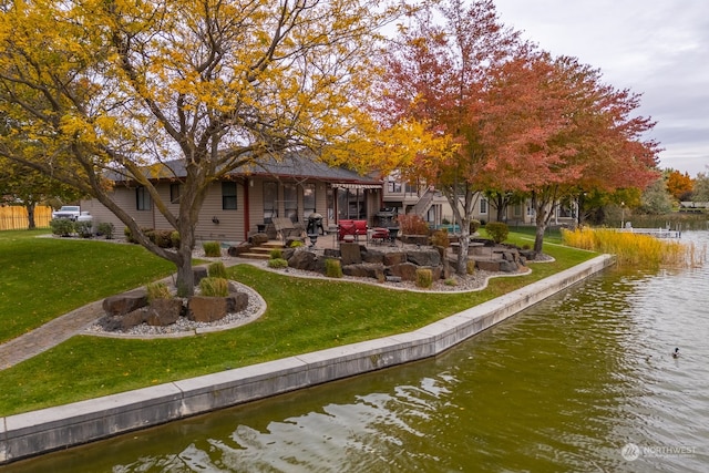 rear view of house featuring a patio, a yard, and a water view