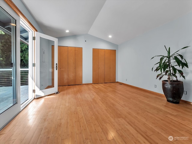 empty room featuring light hardwood / wood-style floors, vaulted ceiling, and a wealth of natural light