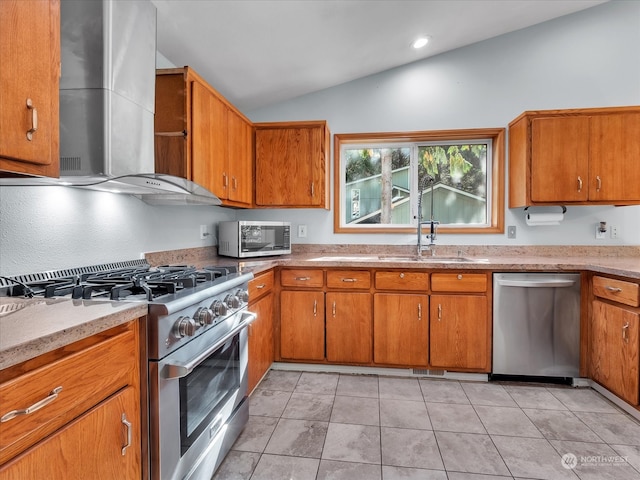 kitchen with wall chimney range hood, light tile patterned floors, vaulted ceiling, sink, and stainless steel appliances