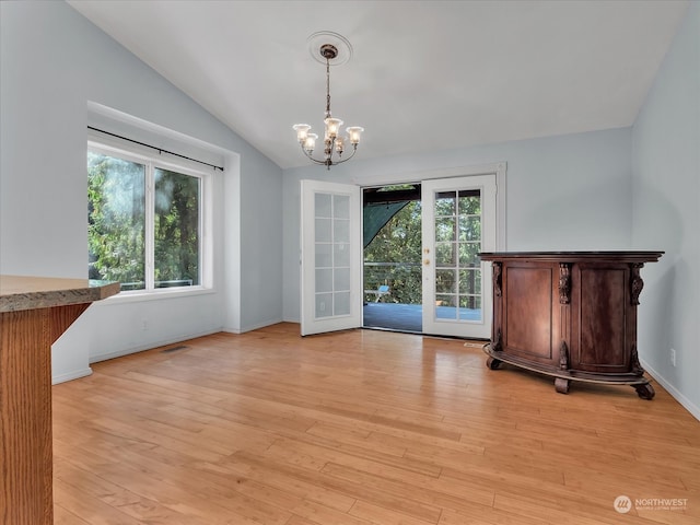 unfurnished dining area with a chandelier, light hardwood / wood-style flooring, and vaulted ceiling