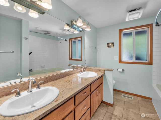 full bathroom with vanity, tiled shower / bath combo, toilet, and tile patterned flooring