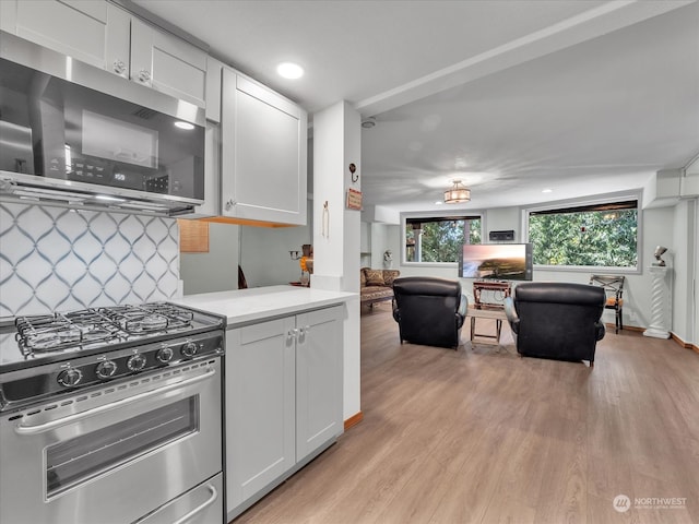 kitchen with appliances with stainless steel finishes, decorative backsplash, white cabinetry, and light hardwood / wood-style floors