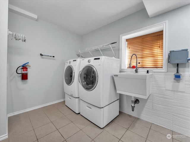 laundry area with sink, washing machine and dryer, and light tile patterned floors