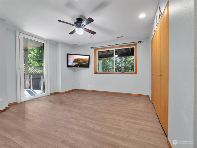 spare room featuring light wood-type flooring, plenty of natural light, and ceiling fan