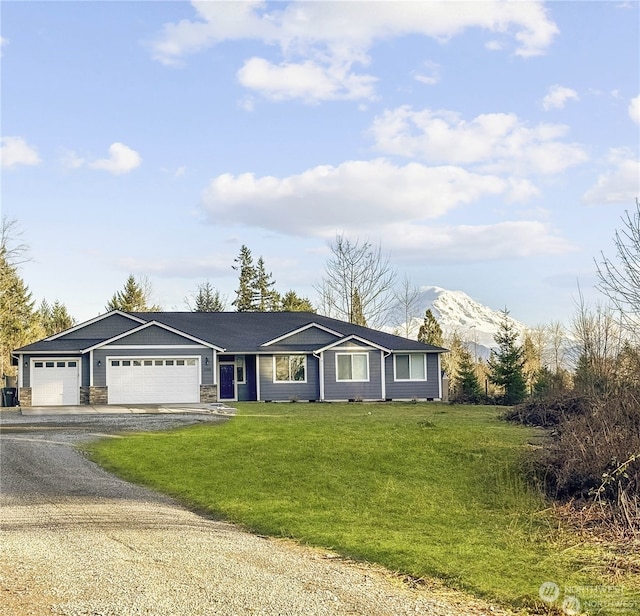 single story home featuring a mountain view, a front lawn, and a garage