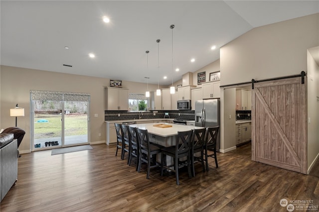 dining area featuring dark wood-type flooring, vaulted ceiling, and a barn door