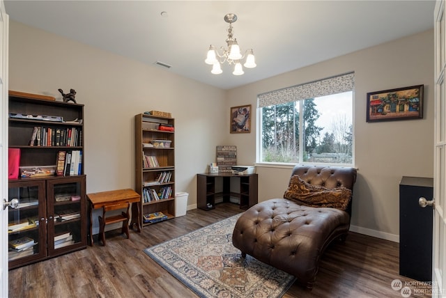 sitting room featuring dark wood-type flooring and a notable chandelier