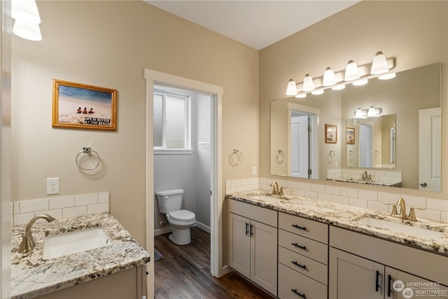 bathroom featuring vanity, hardwood / wood-style flooring, toilet, and tasteful backsplash