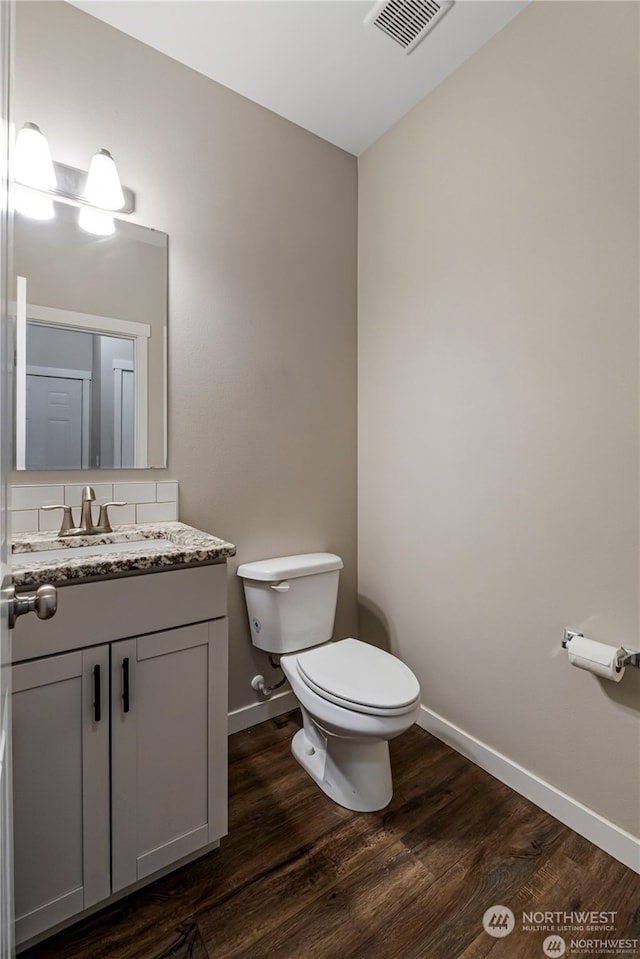 bathroom with toilet, hardwood / wood-style flooring, and vanity