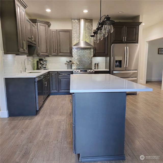 kitchen featuring sink, appliances with stainless steel finishes, wall chimney range hood, and a kitchen island