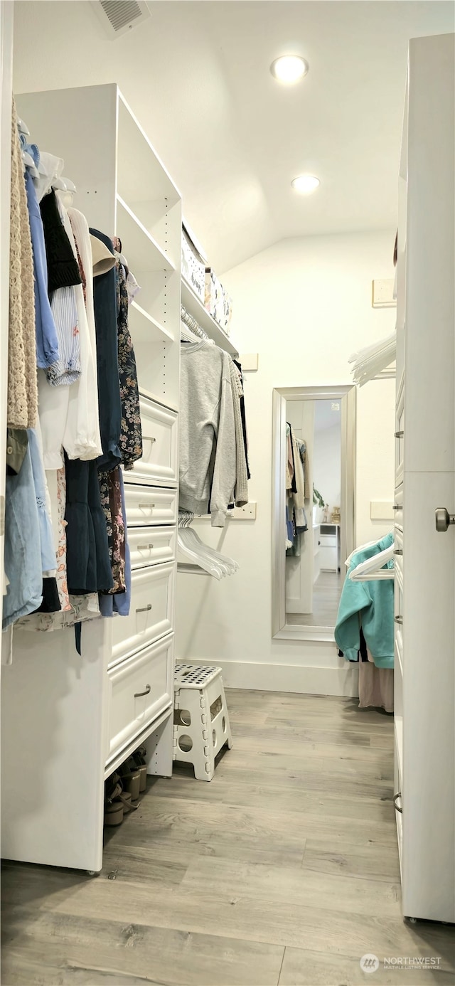 walk in closet featuring light hardwood / wood-style flooring and vaulted ceiling