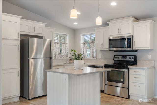 kitchen with lofted ceiling, white cabinets, hanging light fixtures, a kitchen island, and appliances with stainless steel finishes