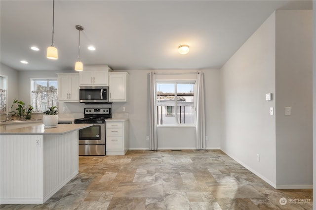 kitchen featuring stainless steel appliances, a wealth of natural light, pendant lighting, and white cabinets