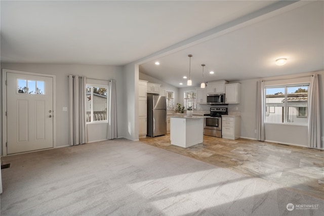 kitchen with appliances with stainless steel finishes, a kitchen island, lofted ceiling with beams, hanging light fixtures, and white cabinetry