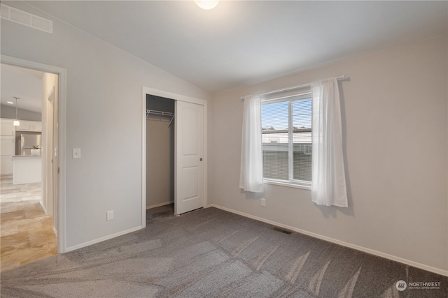 unfurnished bedroom with lofted ceiling, carpet flooring, and a closet