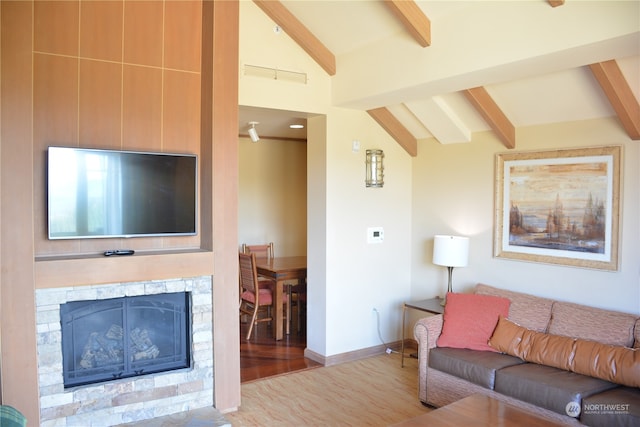 living room with light hardwood / wood-style floors, lofted ceiling with beams, and a stone fireplace