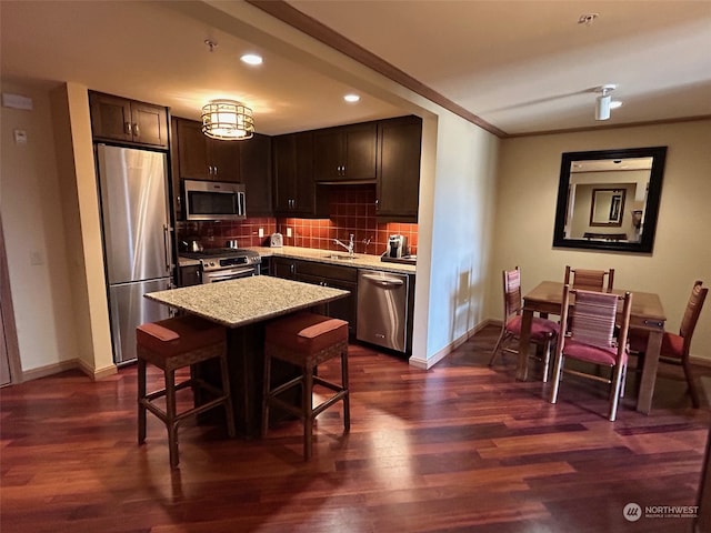 kitchen with dark brown cabinets, backsplash, appliances with stainless steel finishes, dark hardwood / wood-style flooring, and sink