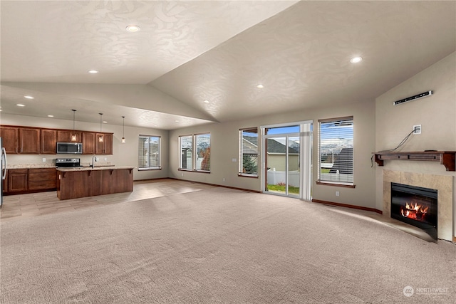 carpeted living room with a tile fireplace, vaulted ceiling, and sink