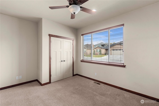 unfurnished bedroom with ceiling fan, a closet, and light carpet