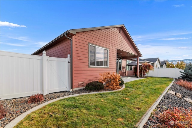 view of side of home with a patio area and a yard