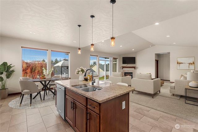 kitchen featuring pendant lighting, lofted ceiling, a center island with sink, sink, and stainless steel dishwasher