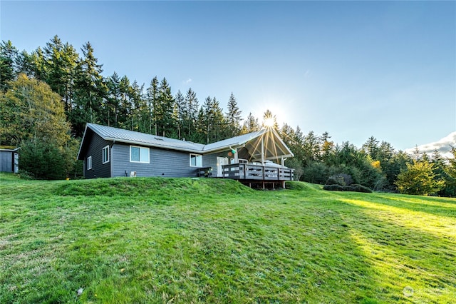 rear view of property with a storage shed, a deck, and a lawn