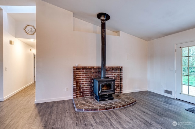 unfurnished living room with a wood stove, lofted ceiling, and hardwood / wood-style floors