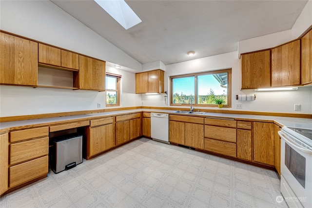 kitchen featuring white appliances, lofted ceiling with skylight, a healthy amount of sunlight, and sink