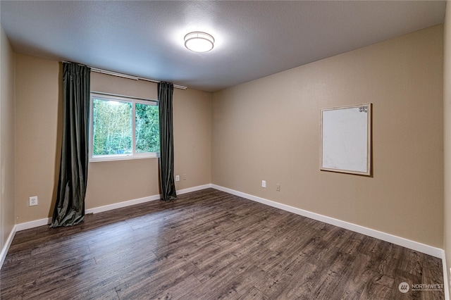 empty room with dark wood-type flooring and a textured ceiling