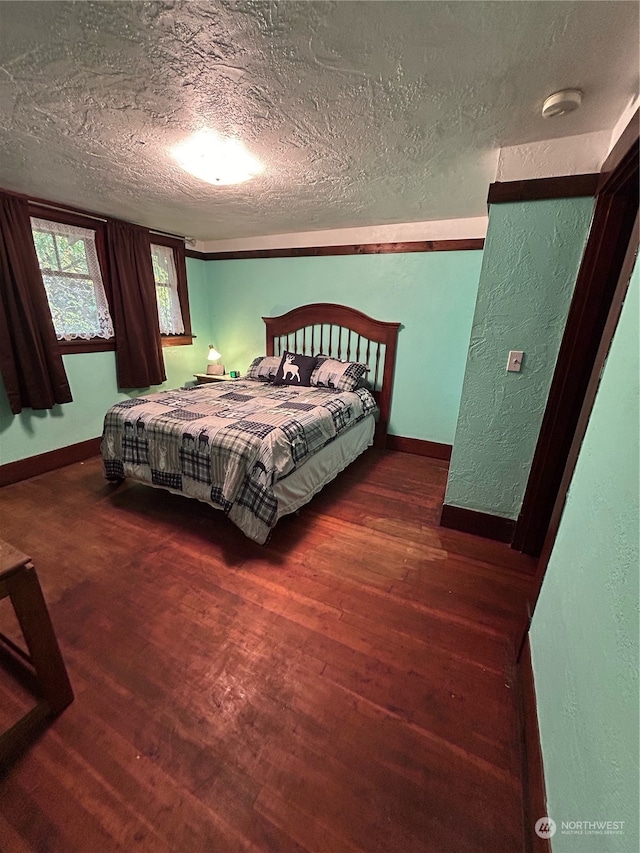 bedroom with a textured ceiling and dark hardwood / wood-style floors