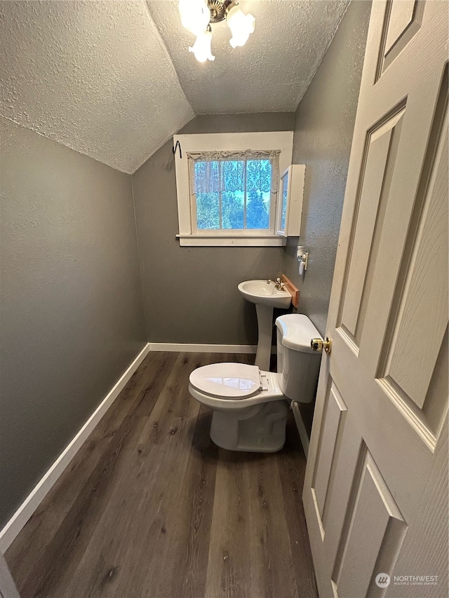 bathroom featuring lofted ceiling, a textured ceiling, hardwood / wood-style flooring, toilet, and sink