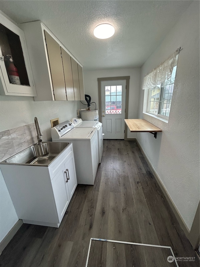 washroom with sink, a textured ceiling, dark hardwood / wood-style flooring, washer and clothes dryer, and cabinets