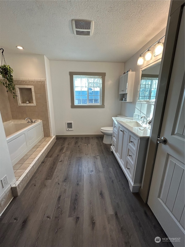 bathroom featuring a washtub, hardwood / wood-style floors, toilet, heating unit, and vanity