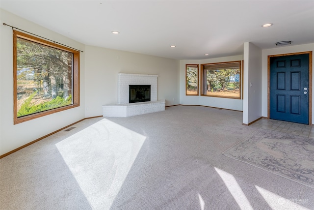 unfurnished living room featuring a brick fireplace and light colored carpet