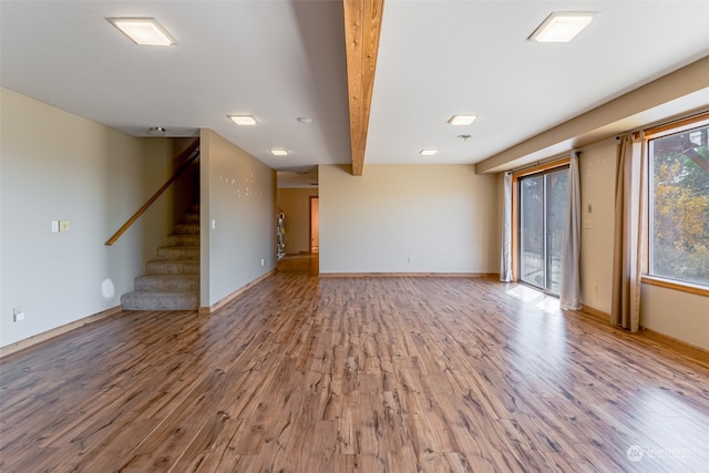 unfurnished living room featuring beamed ceiling and wood-type flooring