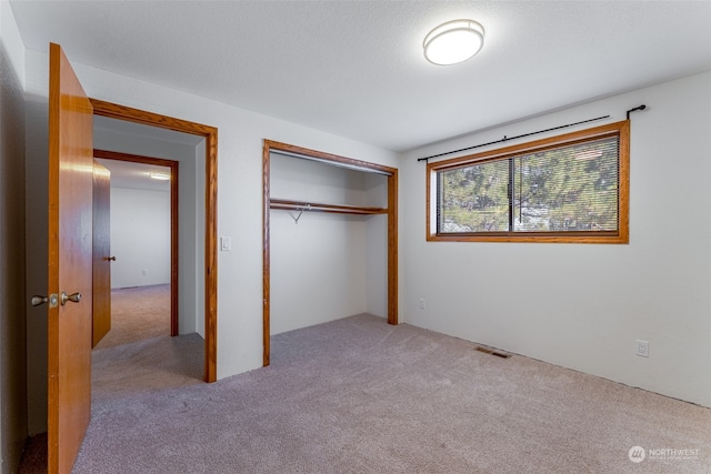 unfurnished bedroom featuring light colored carpet and a closet